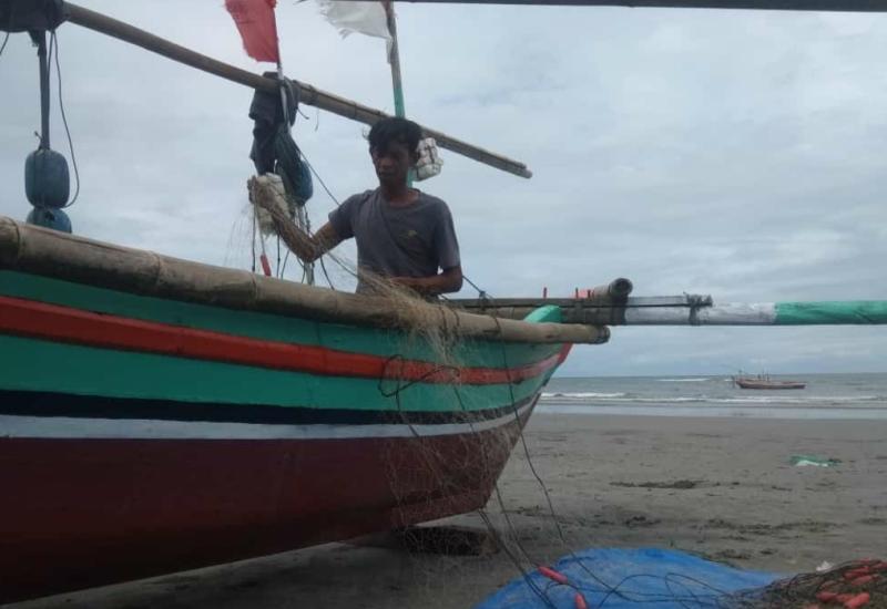 Nelayan Malabero yang tidak melaut sembari memperbaiki jaring yang dipakai untuk melaut.